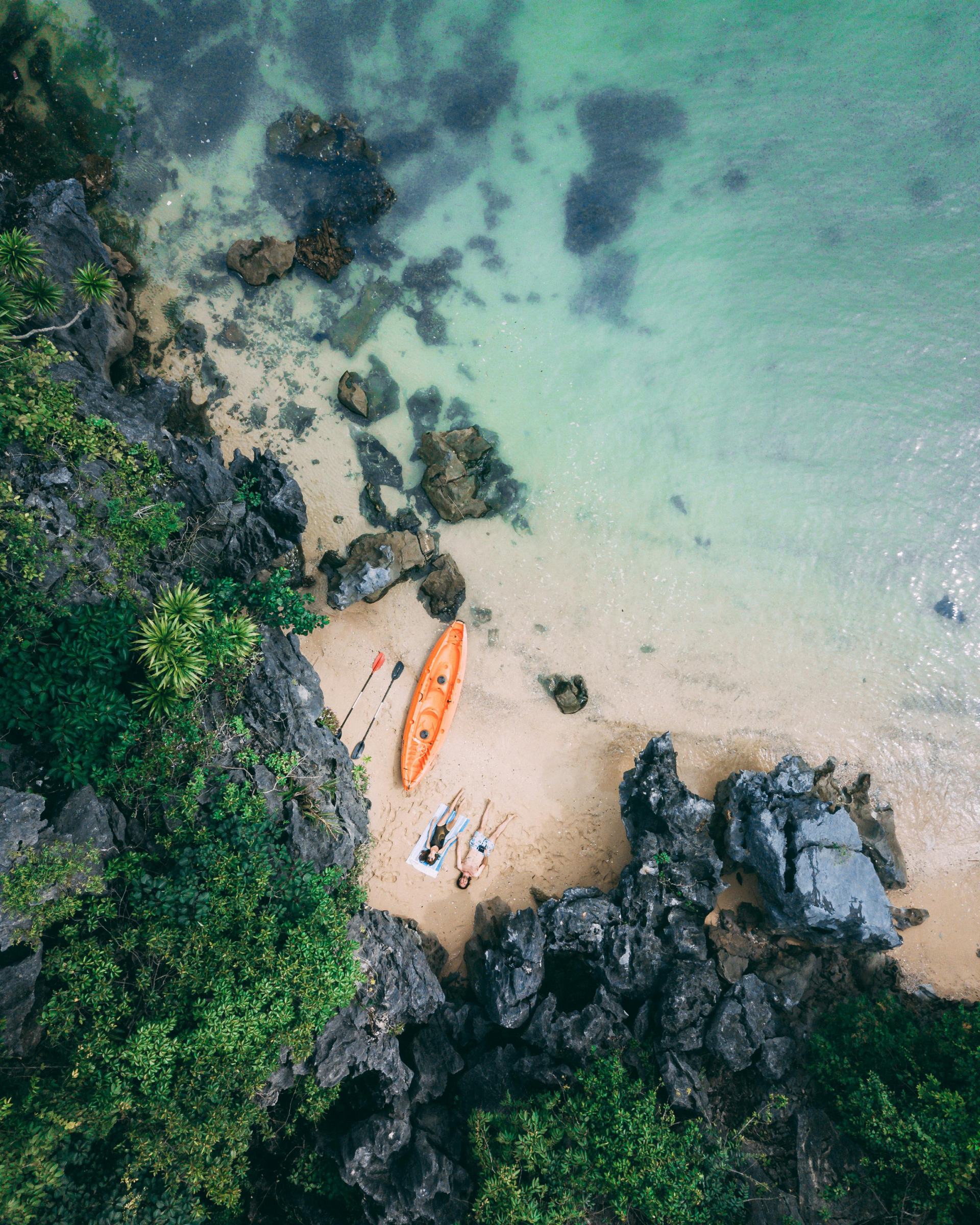 Bird's eye view of a beach featuring golden sand and a boat floating nearby in the ocean