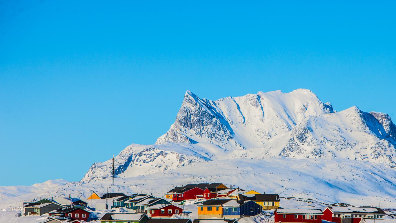 Traditional cabin in snowy Ilulissat at twilight, warm lights glowing, surrounded by frosted trees, reflecting Greenlandic culture. untitled-design-12