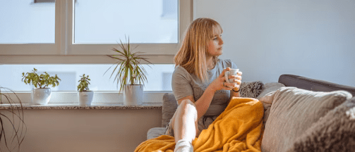 a woman sitting on a couch holding a glass of water