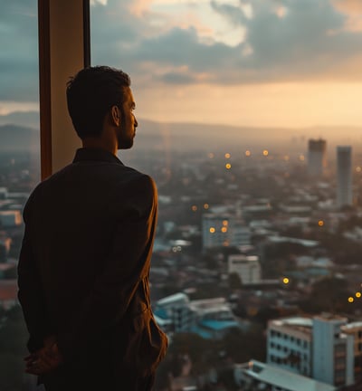 A man standing in front of a window with a view of the ocean