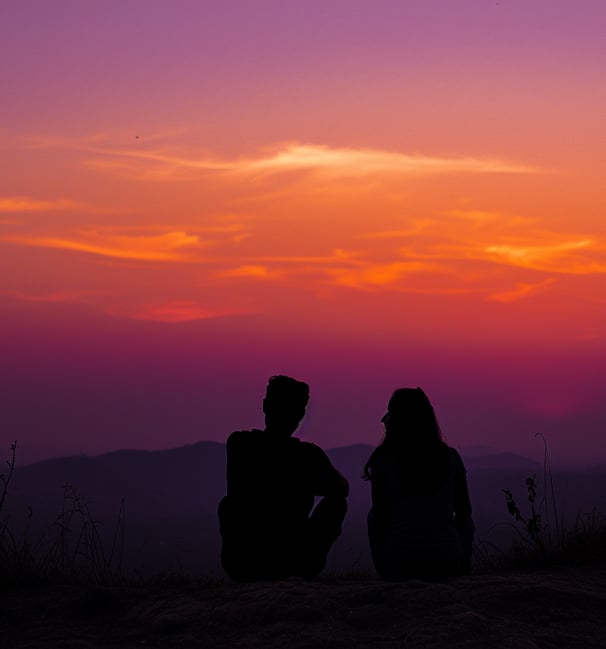 Couple silhouetted against the vibrant sunset at Sunset Point, with the dramatic hues of orange and