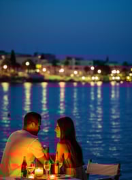 A couple enjoying served Greek cuisine by the bay of Hersonissos-Crete in Greece during the evening. A couple enjoying served Greek cuisine by the bay of Hersonissos-Crete in Greece during the evening.