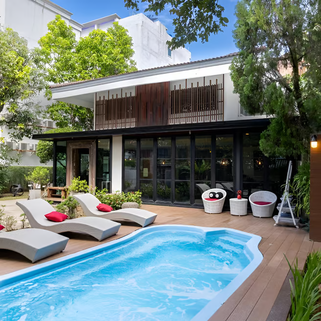 A pool with lounge chairs outside a villa A pool with lounge chairs outside a villa