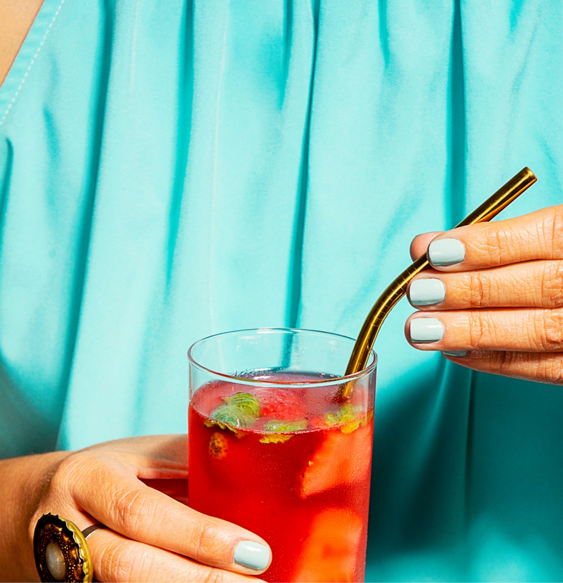 A lady holding a beverage and a straw.