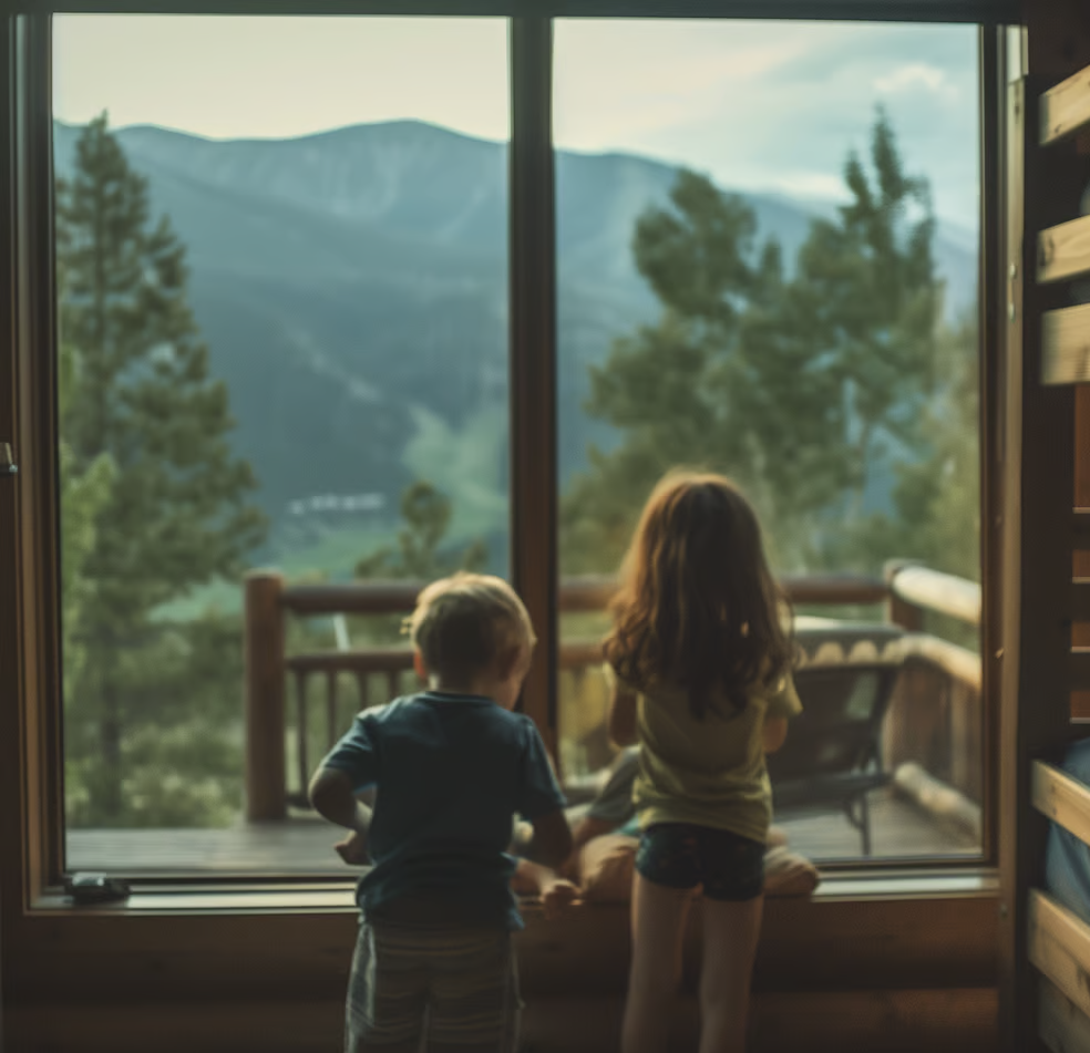 two children standing in front of a window with a mountain view