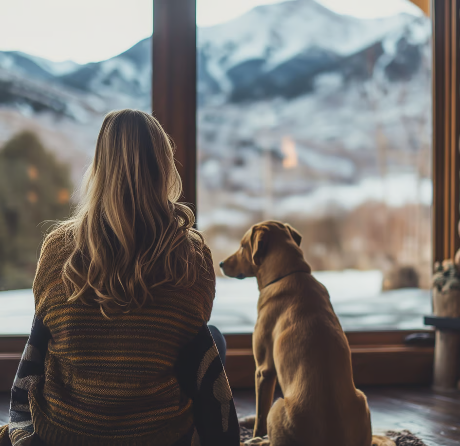 a woman sitting on a rug in front of a fireplace with her dog