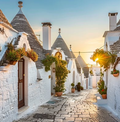 A cobblestone street with white houses on the side in Alberobello, Italy