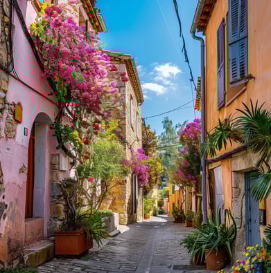 A narrow street with a cobblestone road and flower-adorned homes in Bormes les Mimosas, France