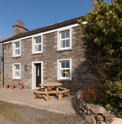 A stone house with a picnic table outside in derbyhaven 