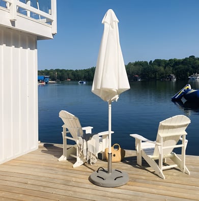 A white umbrella and two chairs on a deck of a cottage in Ontario