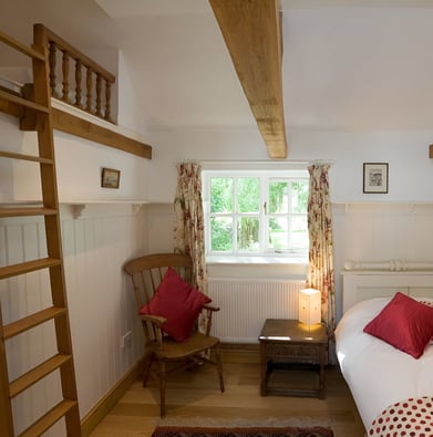 A bedroom with a ladder to climb a loft of a cottage in England