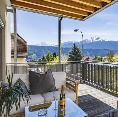 A balcony with a couch and a table with a bottle of wine in innsbruck, austria