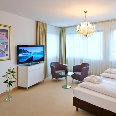 A bedroom with a bed, chair, and television inside an apartment in innsbruck, austria