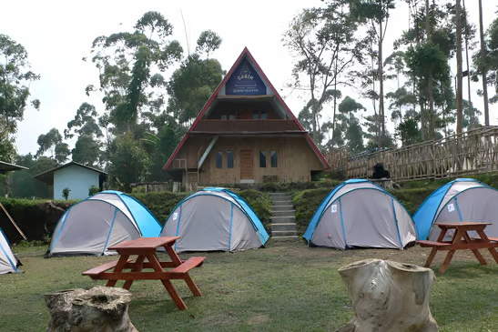 Tents pitched and picnic tables in front of a hut in pagalengan, indonesia Tents pitched and picnic tables in front of a hut in pagalengan, indonesia