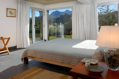 A bedroom with a bed and a chair with the view of the mountains in llao llao, argentina A bedroom with a bed and a chair with the view of the mountains in llao llao, argentina