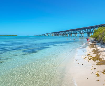 Family enjoying the sandy shores of Bahia Honda State Park with the old railroad bridge in the backd