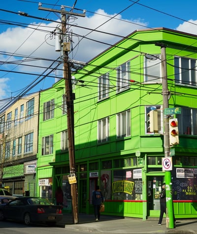 Green building with shops on the street level and traffic in front. Green building with shops on the street level and traffic in front.