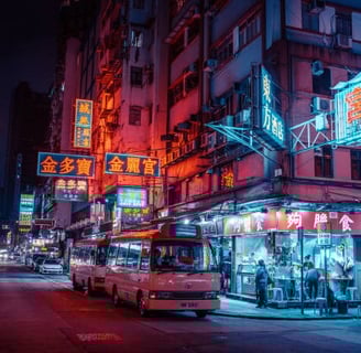 A bustling city street at night illuminated by colorful neon signs