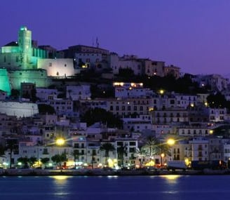 City skyline at night with a glowing green tower