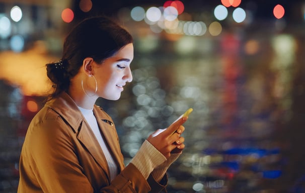 a woman in a tan jacket is looking at her phone