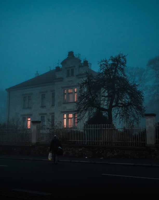 A person walking in front of a house in the fog