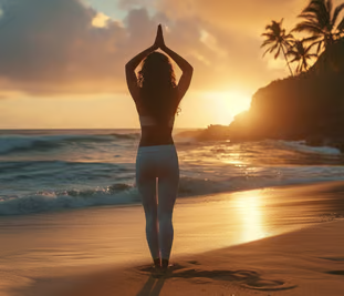 A woman standing on a beach with her arms up in the air