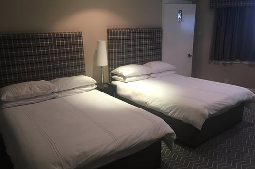 two beds in a hotel room with a lamp on the side in southside glasgow