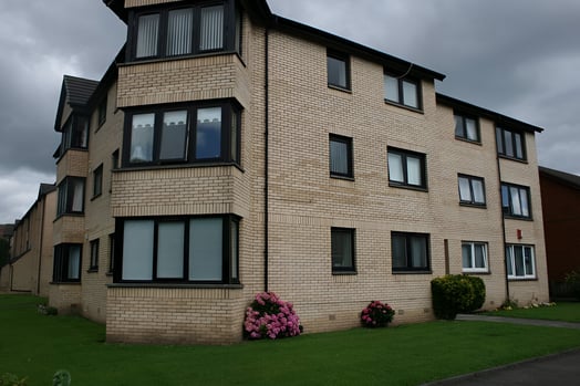 a three-story building with a grass lawn in east end glasgow