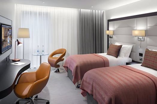 a hotel room with two beds and a desk in merchant city glasgow