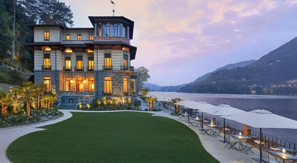 A picturesque villa situated by a serene lake, surrounded by majestic mountains, showcasing nature's beauty.