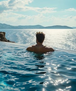 a man in a pool with a view of the ocean