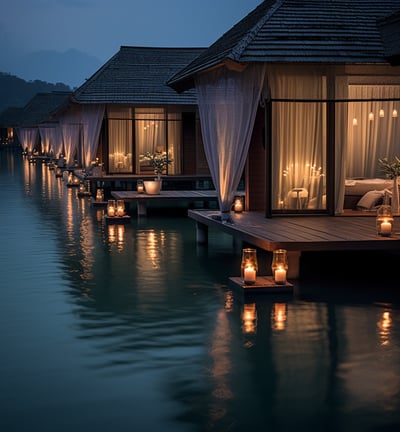 Water villas lined up along a tranquil night sky, illuminated by soft lights reflecting on the calm water below.