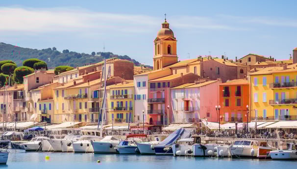 the iconic port area of Saint-Tropez, with a row of colorful buildings and parked boats