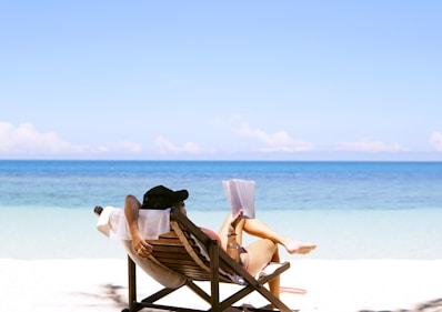 woman sits on brown wooden beach chair