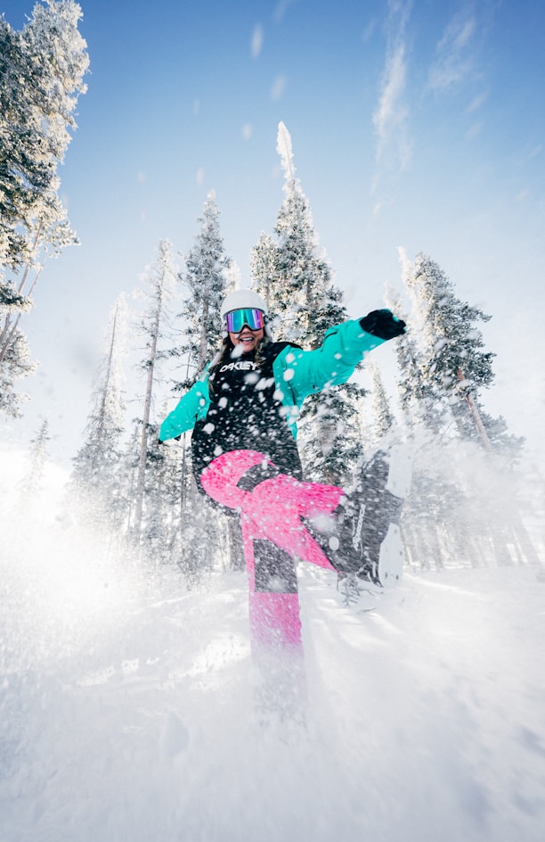 person in blue jacket and pink pants riding on snowboard during daytime