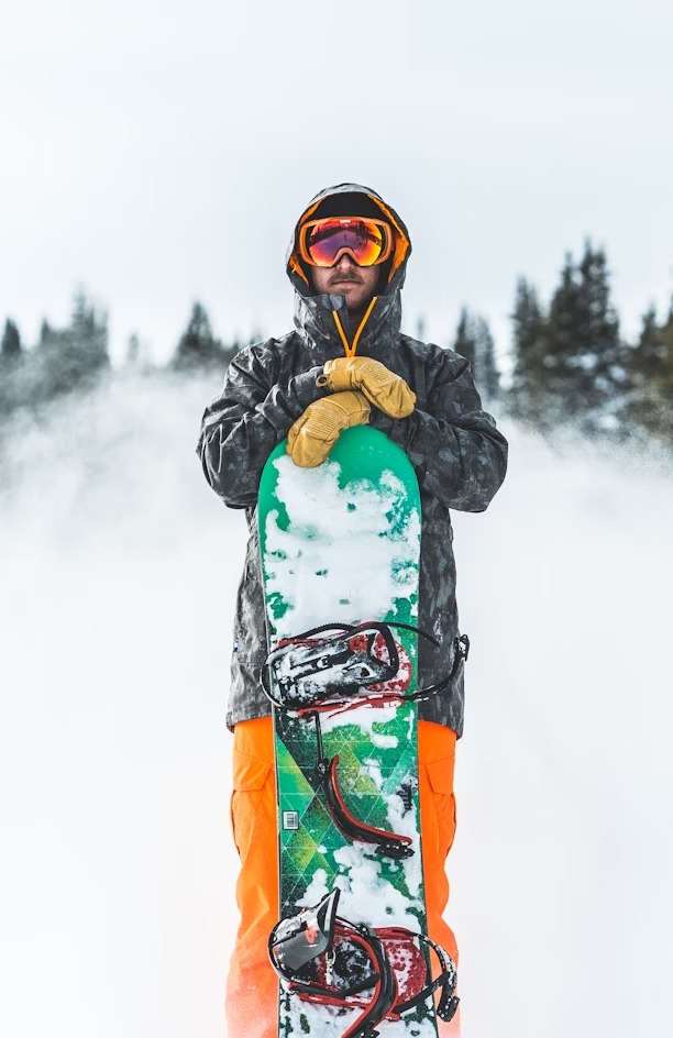 person in blue jacket and green pants wearing black and red snow goggles