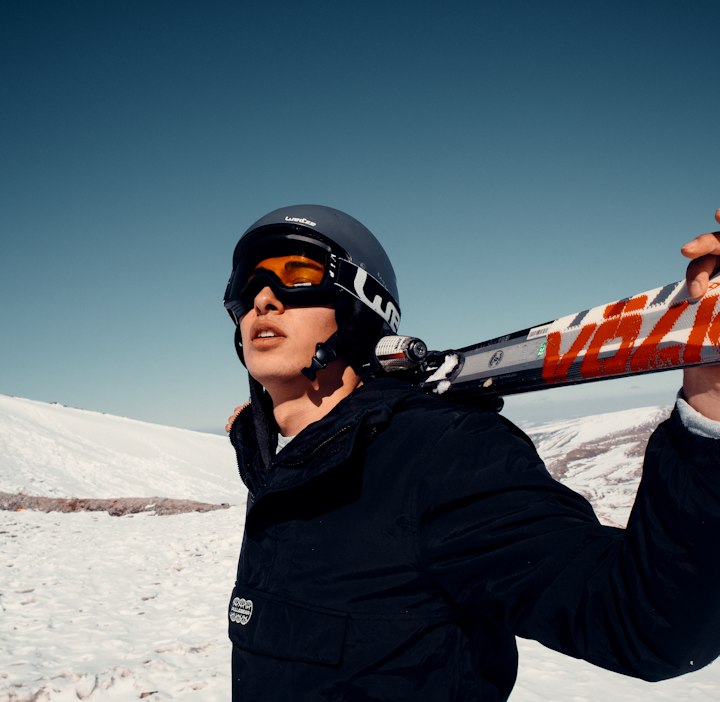 man in black jacket wearing black helmet and black goggles standing on snow covered ground during