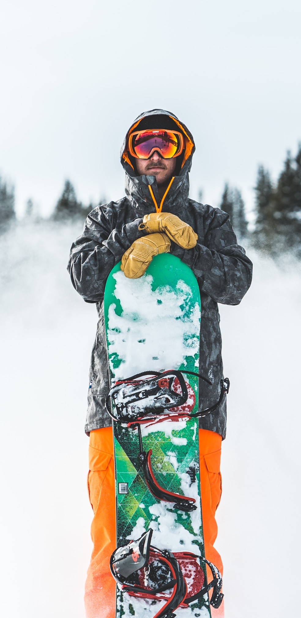 person in blue jacket and green pants wearing black and red snow goggles