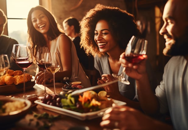 a group of people sitting at a table with wine glasses and food