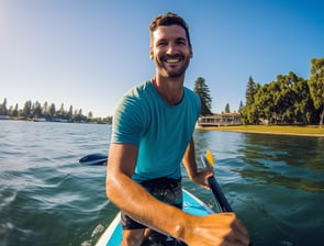 a man in a blue shirt is sitting on a paddle board