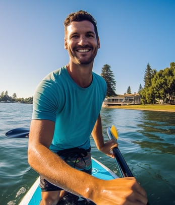 a man in a blue shirt is sitting on a paddle board