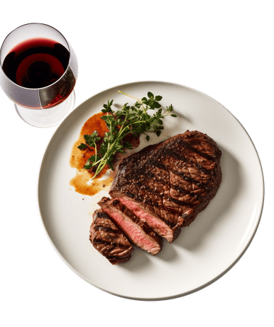 top shot of steak on a white plate with wine