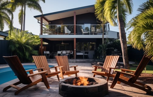 A fire pit in front of a house with chairs and palm trees, perfect for cozy outdoor gatherings.
