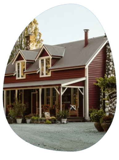 Rural New Zealand lodge with maroon cladding and white trim under a clear sky, suggesting a homely base for Lake Taupo advent Rural New Zealand lodge with maroon cladding and white trim under a clear sky, suggesting a homely base for Lake Taupo advent