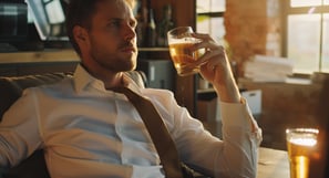 Businessman with untied tie, drinking beer.