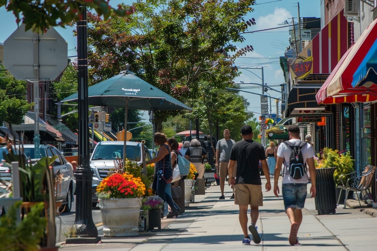 a group of people walking down a sidewalk in long island, new york