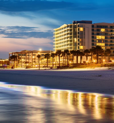 a beach at nighttime with a view of a hotel