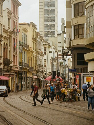 Pedestrians walking along a city street with a clock tower in the background