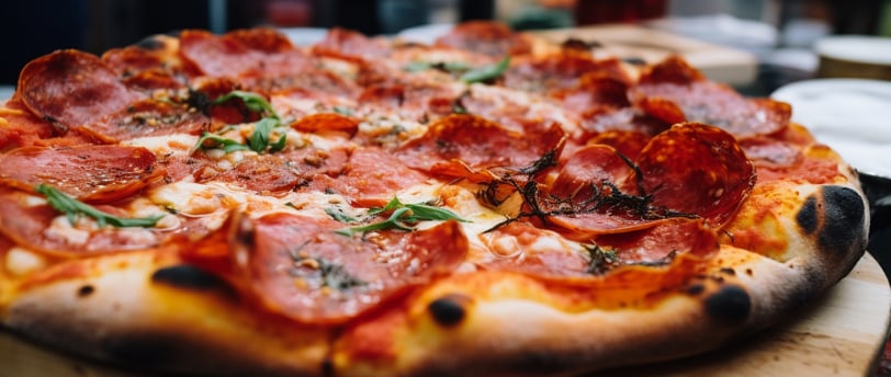 a pizza with pepperoni and basilo sauce