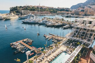 A picturesque view of Monaco's harbor filled with luxurious yachts and boats against a stunning coastal backdrop